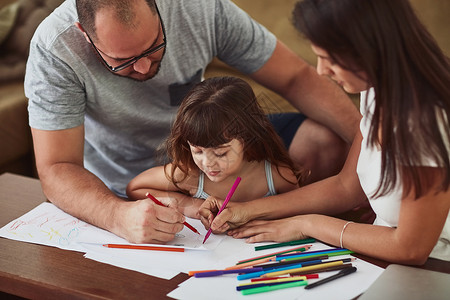 创意表达对这个家庭很重要 一对妈妈和爸爸带着他们年幼的女儿在家里一起画画关爱高清图片素材