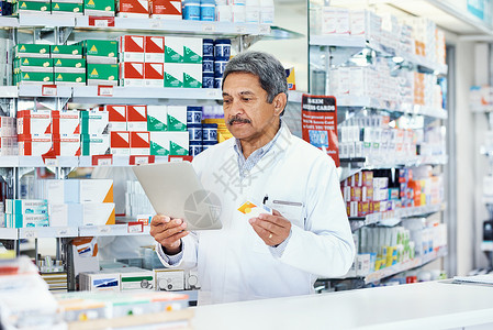 他总是在他的药房里更深入地读到产品 一位成熟的药剂师使用化学家用的数字片片药店高清图片素材