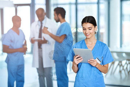 检查她的日常医疗职责 一位年轻的医生在医院和她的同事在后台使用数字平板电脑背景图片