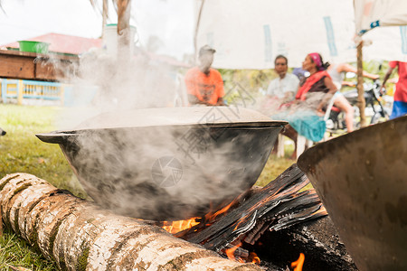 无法辨认的土著人在用棕榈木制成的营火上煮锅炉汤背景图片
