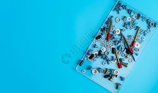 蓝色背景塑料托盘中的金属螺栓 螺母 垫圈和螺钉的顶视图 紧固件设备 机械技术人员的硬件工具 螺纹紧固件配件 五金螺母和螺栓背景图片