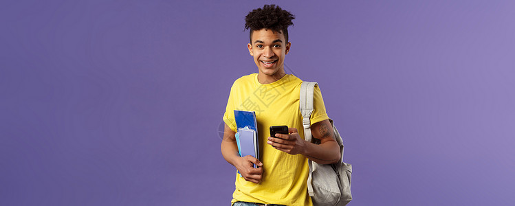 回到学校 大学的概念 年轻英俊微笑男子的肖像 学生要求同学电话号码 在手机上做笔记 背着背包 拿着笔记本和学习材料招聘投资职业教背景图片