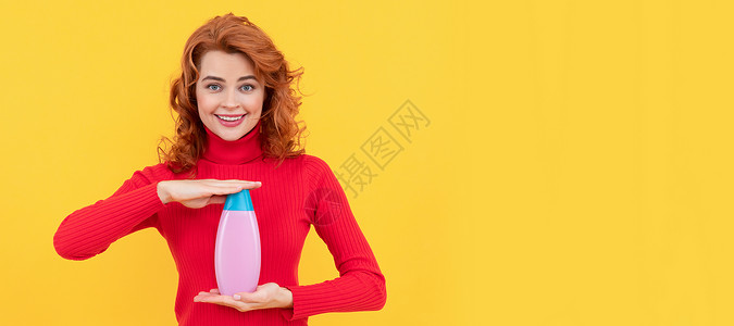 喜悦的红发女人卷发染色头发 展示了洗发水 广告背景图片