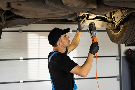 专业机械师正在汽车服务中修理汽车 在车间工作的带灯的蓝色工作服的汽车机械师 汽车服务 维修 保养和人的概念车辆高清图片素材