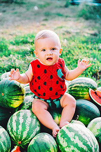 小婴儿和西瓜快乐的小男婴坐在西瓜田或花园里 快乐的婴儿微笑着 看着相机 孩子在户外吃水果 健康的生活方式概念幸福晴天童年食物野餐公园裙子小吃背景