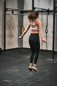 健身房跳绳子在健身房跳过绳子的年轻女子 跑到健身房去背景