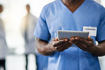 身体健康掌握在他手中 一位医生和他的同事在后台使用数字平板电脑背景图片