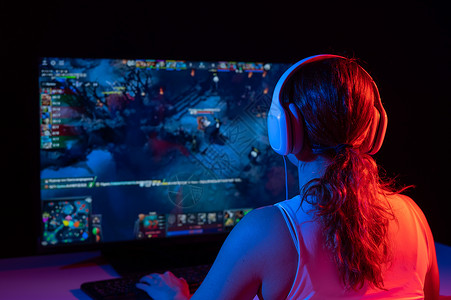 动漫黑岩射手一名白人女性在黑暗中在霓虹灯下玩电脑游戏的后视图锦标赛喜悦技术电脑老鼠比赛键盘娱乐竞赛游戏背景