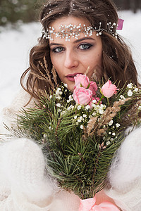 美丽雪中玫瑰美丽的新娘穿着白色的裙子 在白雪皑皑的冬季森林里捧着一束花 大自然中新娘的画像童话女孩女士风格沉淀仪式已婚乡村庆典派对背景