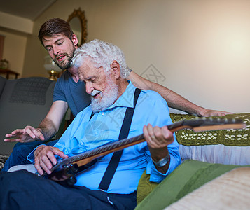 一个快乐的年轻人 教他老爷爷在家里沙发上弹电吉他 (笑声) 我和孩子们一起唱了两首诗背景图片