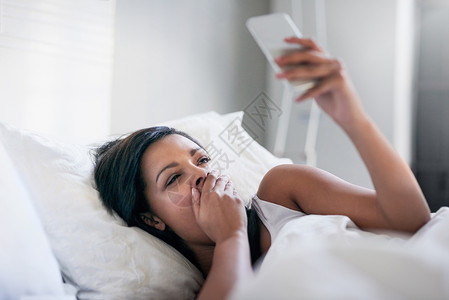早上在社交媒体上没什么有意思的 睡着的年轻女人在家床上醒过来了背景图片