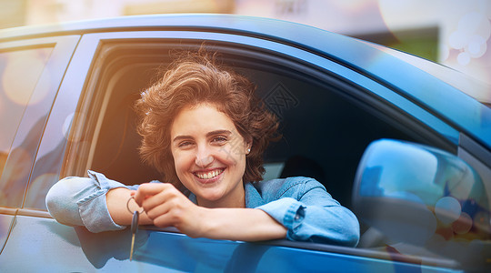 幸福是 得到你的第一辆汽车 一个快乐的年轻女人拿着新车的钥匙驾驶高清图片素材