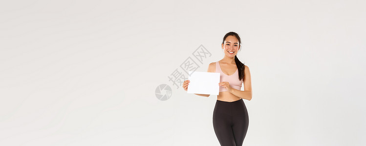 会员专属福利全长微笑漂亮的亚洲黑发女运动员 穿着运动服的女运动员在空白纸上展示标志 广告健身房会员或健身器材特价训练情绪举牌子身体成人肌肉女背景