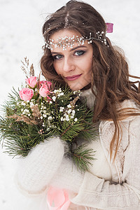 美丽雪中玫瑰穿着白裙子的美丽新娘 在雪覆盖的冬季森林中穿着花束带 自然界新娘的肖像庆典宴会订婚女性风格化妆品餐厅派对婚礼乡村背景