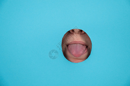 女人在蓝纸背景的洞里用舌头说话背景图片