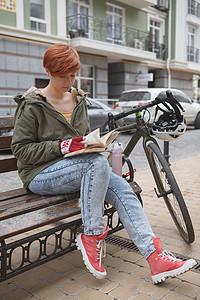 可爱的年轻女子骑自行车在城市街道上女性碎石有氧运动街道越野赛服饰潮人学习享受车辆背景图片