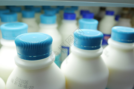 牛奶瓶架子装在架子上塑料瓶里的新牛奶零售奶制品展示动作奶牛白色蓝色奶油店铺瓶子背景