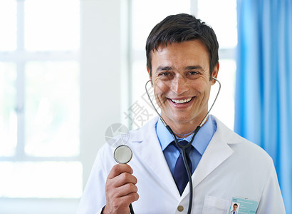 我们看看里面有什么 英俊年轻医生的肖像微笑着拿着听诊器呢? - 是的药品高清图片素材