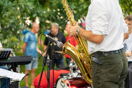 男子小号演奏萨xphonist男子在街头节日表演中演奏萨克斯风时正在玩的Saxhophone背景