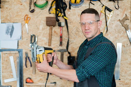 一名男子在车间用电锯锯木头的肖像木工修理工材料男性木匠硬木锯末工匠职场家具乐器高清图片素材