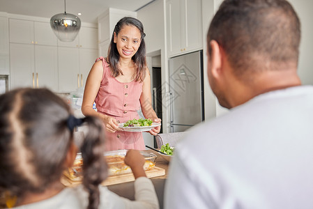 健康 纯素的母亲和家人在家里的厨房餐桌上享用午餐 正餐或一起吃的沙拉 妈妈 爸爸和孩子有自制的食物 健康生活方式的绿色蔬菜小吃背景图片