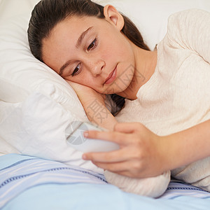 爱不释手 一个十几岁的女孩躺在床上用手机发短信高清图片