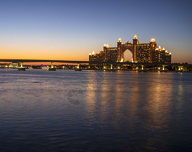 Atlantis 迪拜的五星级酒店很受欢迎 UAE在晚上 在照片中也可以看到通向旅馆的单轨铁路喷泉停留日落建筑旅游反射天空假期建背景