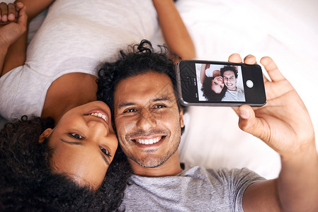 一个可爱的情侣在床上拍个自拍片背景图片