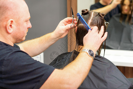 在职业美容院 男发型师剪女客户的头发理发师顾客镜子女性黑发发型造型师沙龙治疗客厅修剪高清图片素材