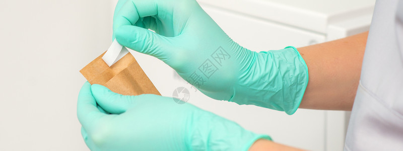 戴绿色保护手套的美人手持一个手工信封 在消毒前对工具进行消毒诊所清洁度乐器机器程序镊子女士牙医消毒器科学家背景图片
