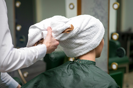 理发师在美容院洗完澡后 用毛巾包着年轻女子的湿头发理发顾客女性理发店服务护发素护理女孩职业工作漂亮的高清图片素材