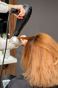在美发工作室吹干头发 在美容院 女美发师造型师用吹风机和圆刷红头发吹干头发职业工作美容师洗发水梳妆台沙龙女性摄影治疗两个人顾客高清图片素材