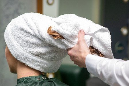 理发师在美容院洗完澡后 用毛巾包着年轻女子的湿头发治疗顾客服务发型女士店铺温泉女孩沙龙洗发水女性高清图片素材