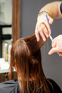 发型剪刀男性发型师在理发厅剪棕色头发 剪剪刀的毛发修剪造型师黑发女性顾客沙龙理发师女孩客厅工人背景