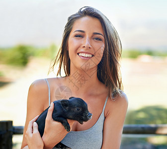 认识农场上的最新成员 一个年轻女人拿着可爱的小猪仔 她很可爱微笑黑发皮肤幸福女性青年青少年宠物小猪动物背景