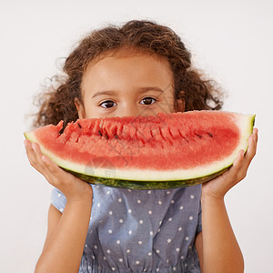 坐着西瓜的孩子一个可爱的小女孩 在嘴前拿着一片西瓜 简直是笑得要命背景