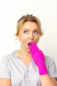 一位年轻的天主教女医生或护士的肖像被用粉色手套手在白色背景上蒙住嘴而震惊 笑声成人女性工作手势外科医师秘密意外棕榈女士覆盖高清图片素材