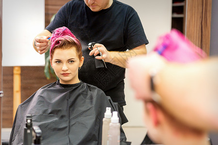 在现代发廊里 美丽的粉红头发的白种美女护理造型师顾客理发师发型沙龙卷曲发型师工作女孩金发高清图片素材
