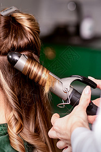 女美发师在美容院里 为一位棕色头发的年轻caucasian女子卷发护理客厅魅力工具造型卷发器女孩职业女性造型师背景图片
