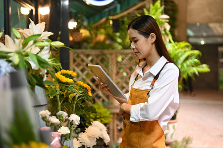 青年妇女小商家花店业主 使用数字平板电脑检查订单 为她的商店订单微笑高清图片素材