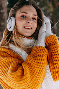 一条耳机素材冬天外面穿黄色毛衣的金发女青年 在雪林里穿着冬装散步的十几岁少女季节手套围巾女性森林化妆品雀斑喜悦暴风雪金发女郎背景