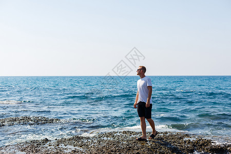 身穿白色T恤和短裤的太阳镜 有魅力的年轻男子 站在地中海海岸上胡须思维推广运动主义休闲太阳蓝色潮人男性背景图片