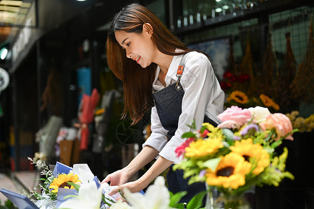 集中的年轻女花商在她的花店制作美丽的花束微笑高清图片素材