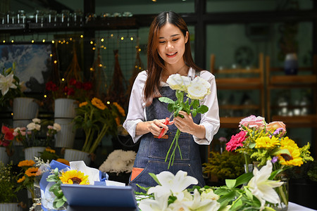 快乐的年轻少女小商业主 在花店做漂亮的花束 在花店店铺高清图片素材