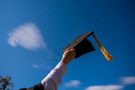 在蓝天上用毕业帽 紧贴着女人的手学士空气学校学生快乐大学帽子女孩手臂文凭流苏高清图片素材