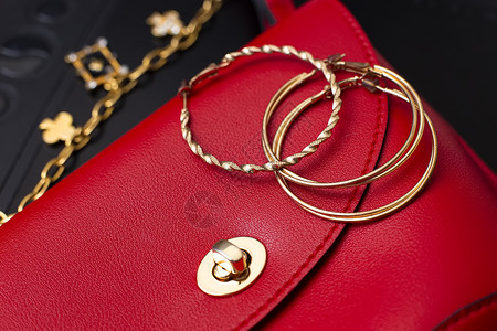 金环耳环和服装首饰躺在一个红色皮包上宝石高清图片素材
