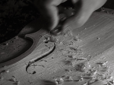小提琴手在车间用拇指平面和暗光雕刻小提琴板建设职业中提琴工作传统艺术精神产品测量工作台背景图片