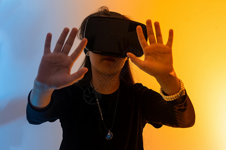 礼谢恩师情一个戴着虚拟现实眼镜头发的少女看电影或玩电子游戏 用双手表达感激之情 有趣的女孩看着 VR 眼镜 手牵着手工具冒充视频互联网青少背景