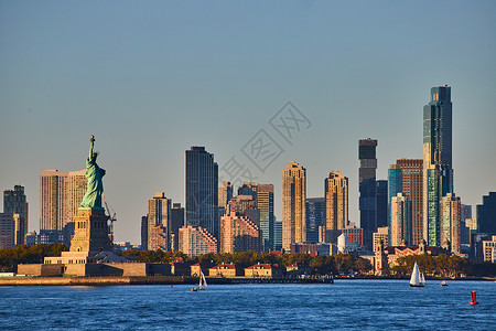 在纽约市自由神像与摩天大楼 在金光中从水中环绕而来背景