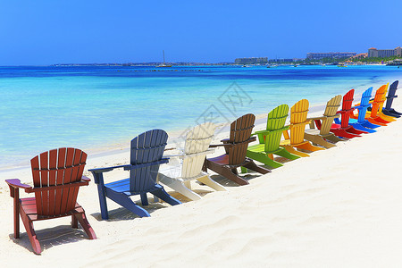 位于阿鲁巴杜斯加勒比的阿鲁巴白沙滩上多彩色木制椅子天空热带海滩海景水湾休闲椅帆船假期躺椅旅游背景图片